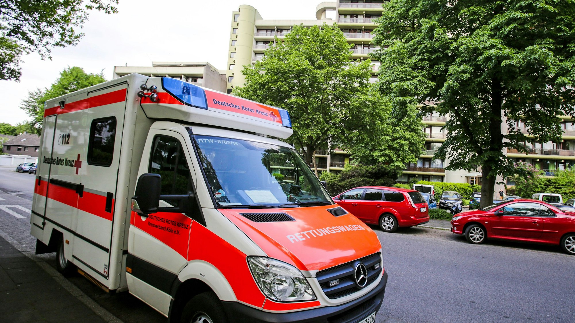 Ein Rettungswagen (RTW) des Deutschen Roten Kreuz (DRK) steht vor einem Wohnhaus am Wiener Weg  in Köln.