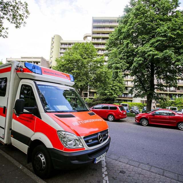 Ein Rettungswagen (RTW) des Deutschen Roten Kreuz (DRK) steht vor einem Wohnhaus in Köln.