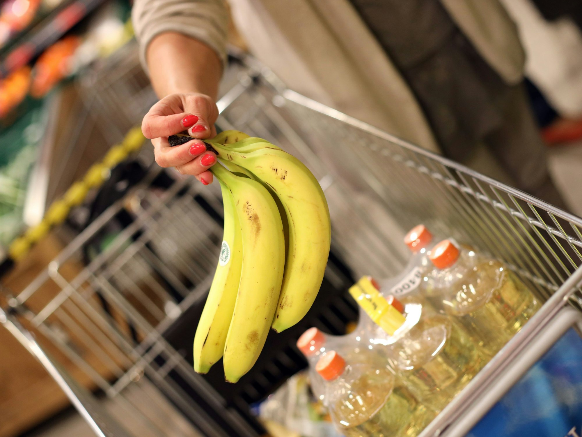 Eine Kundin legt Bananen in ihren Einkaufskorb.