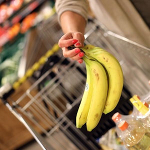 Eine Kundin legt Bananen in ihren Einkaufskorb.