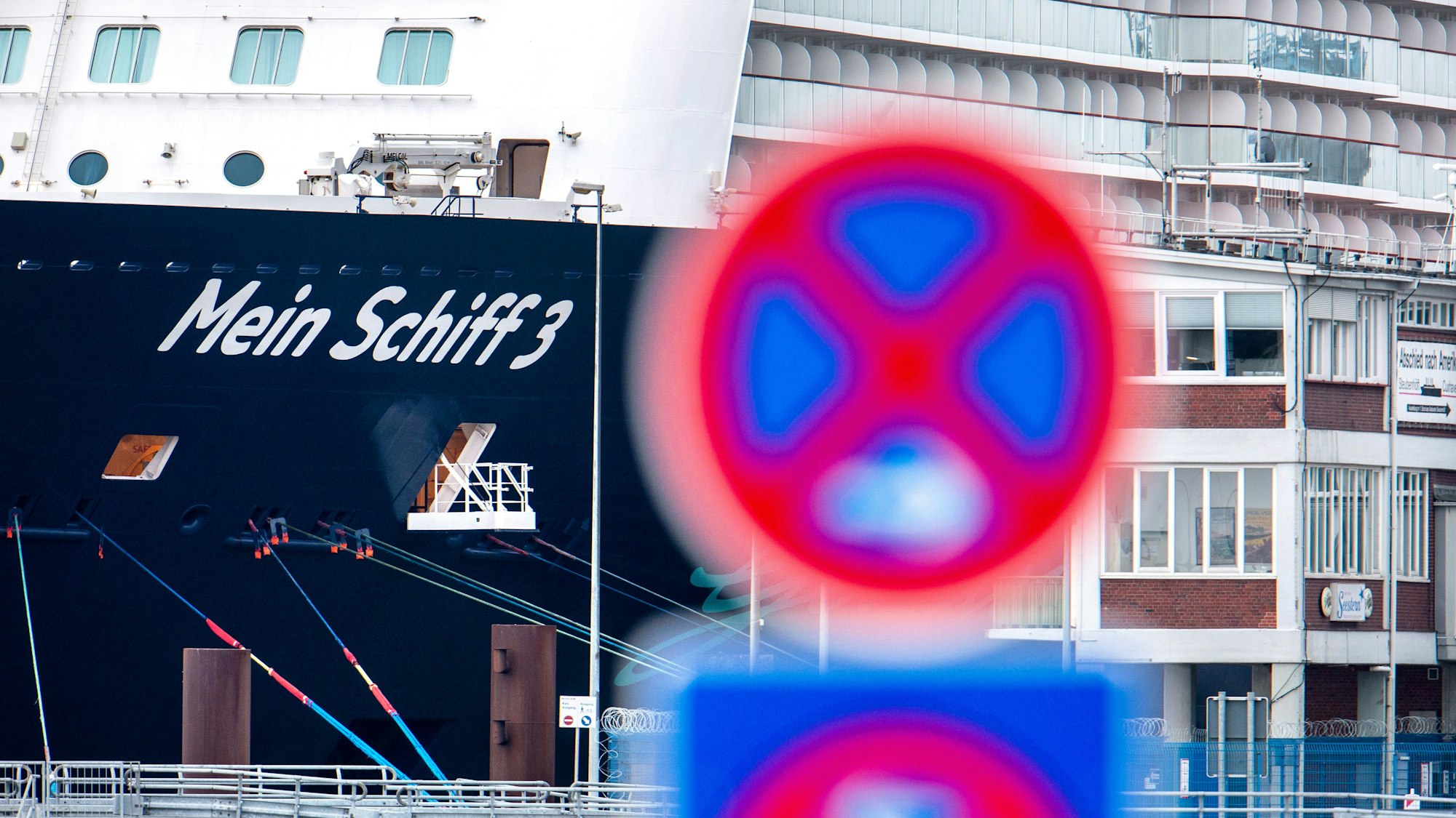 Das Foto aus dem Jahr 2020 zeigt im Hintergrund das Kreuzfahrtschiff „Mein Schiff 3“ von Tui Cruises. Im Vordergrund befindet sich ein rot-blaues Parkverbot-Schild.