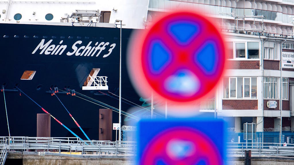 Das Foto aus dem Jahr 2020 zeigt im Hintergrund das Kreuzfahrtschiff „Mein Schiff 3“ von Tui Cruises. Im Vordergrund befindet sich ein rot-blaues Parkverbot-Schild.