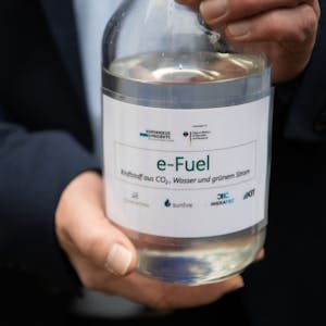 Ein Mitarbeiter einer Karlsruher Forschungsanlage hält eine Flasche mit E-Fuel. Der Kraftstoff soll trotz des Verbots für Verbrennungsmotoren eine Alternative sein.
