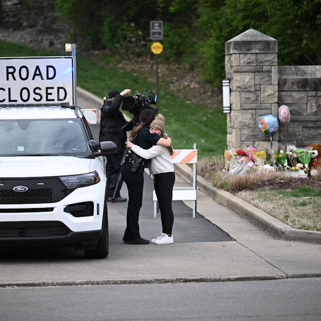 Eine Polizistin und eine andere Frau umarmen sich vor der Zufahrt zur Covenant School in Nashville, Tennessee.