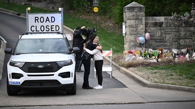 Eine Polizistin und eine andere Frau umarmen sich vor der Zufahrt zur Covenant School in Nashville, Tennessee.