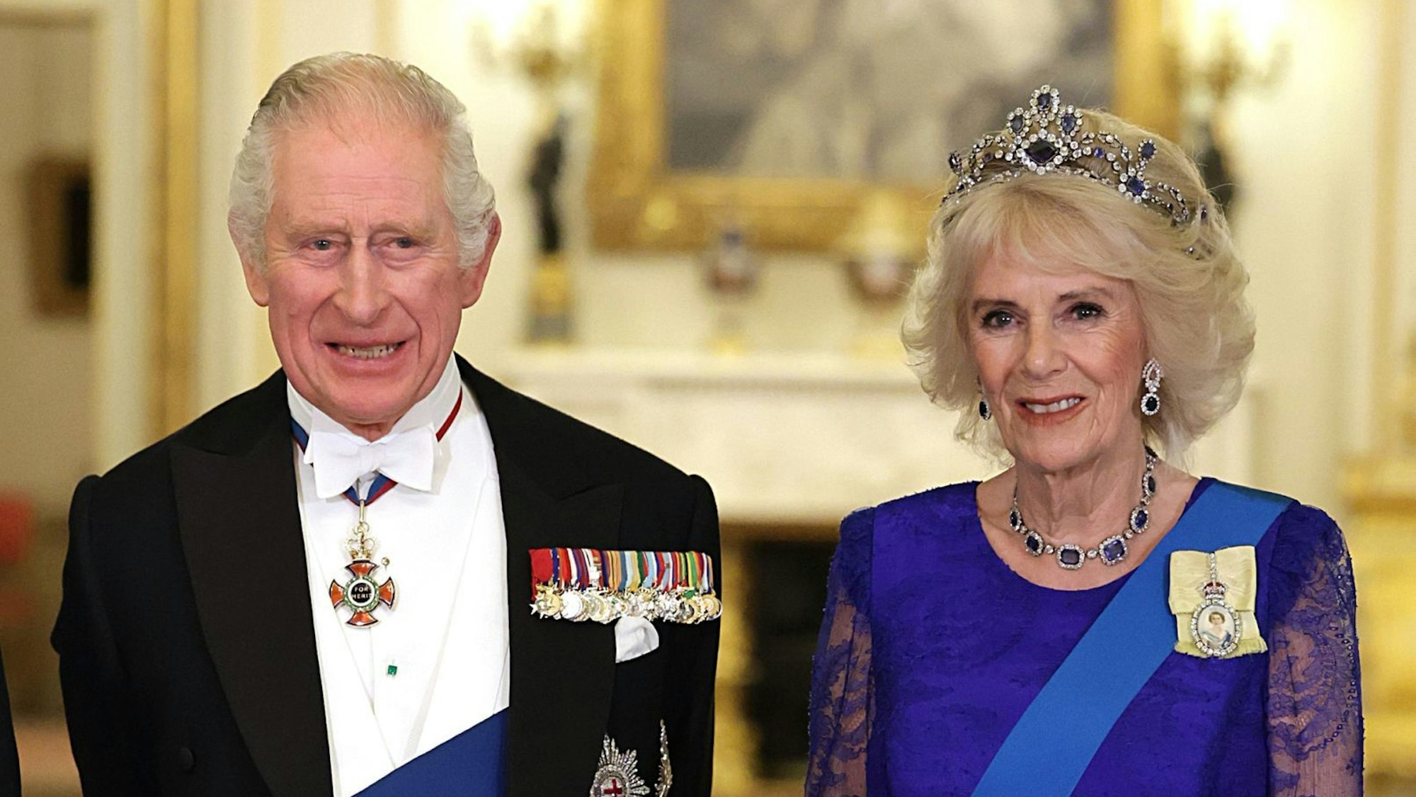 König Charles III. und Königsgemahlin Camilla beim Staatsbesuch in festlicher Kleidung.