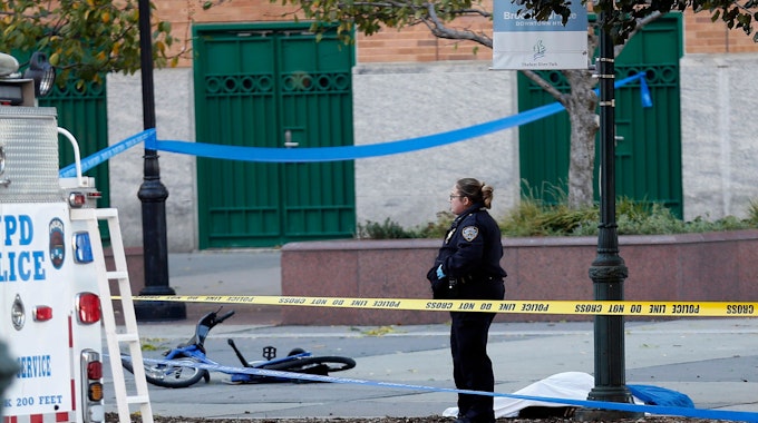 Eine Polizistin steht im Oktober 2017 in New York (USA) auf einem Fahrradweg neben einem abgedeckten Körper und einem beschädigten Fahrrad.