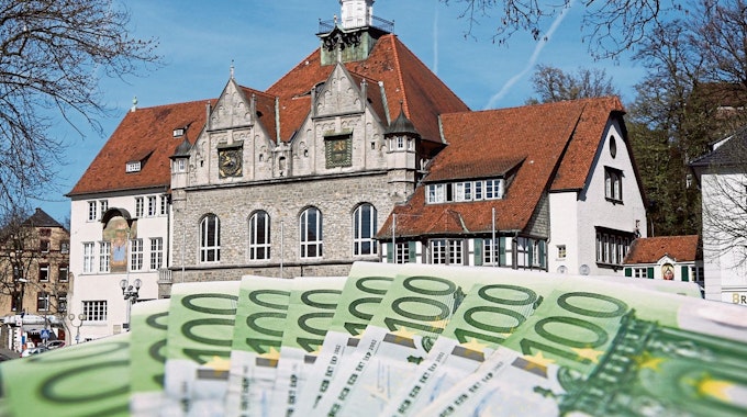 Das Bergisch Gladbacher Rathaus und eine Reihe von 100-Euro-Scheinen.