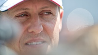Der deutsche Formel-1-Pilot Michael Schumacher blickt lächelnd in die Kamera. Er trägt eine Kappe seines Teams Mercedes.