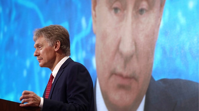 Kremlsprecher Dmitri Peskow hält eine Rede, im Hintergrund wird das Gesicht des russischen Präsidenten Wladimir Putin eingeblendet. Peskow soll nun im privaten Rahmen vor einem langwierigen Krieg gewarnt haben. (Archivbild)