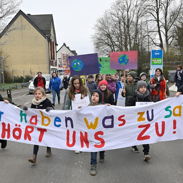 Kinder laufen auf der Straße und halten ein Banner mit der Aufschrift „Wir haben was zu sagen, hört uns zu“.&nbsp;