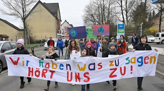 Kinder laufen auf der Straße und halten ein Banner mit der Aufschrift „Wir haben was zu sagen, hört uns zu“.&nbsp;
