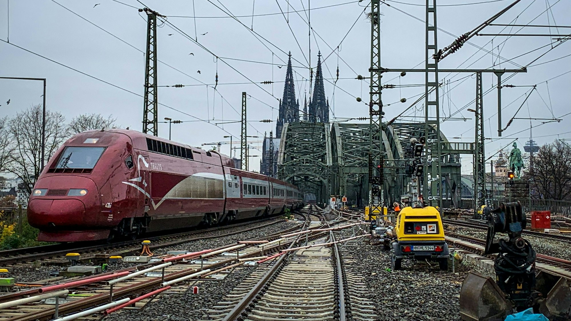 28.11.2022, Bauarbeiten an den Weichen im Bahnhof Köln Messe/Deutz sind zu sehen. Im Hintergrund der Dom und links im Bild ein roter Thalys-Zug.