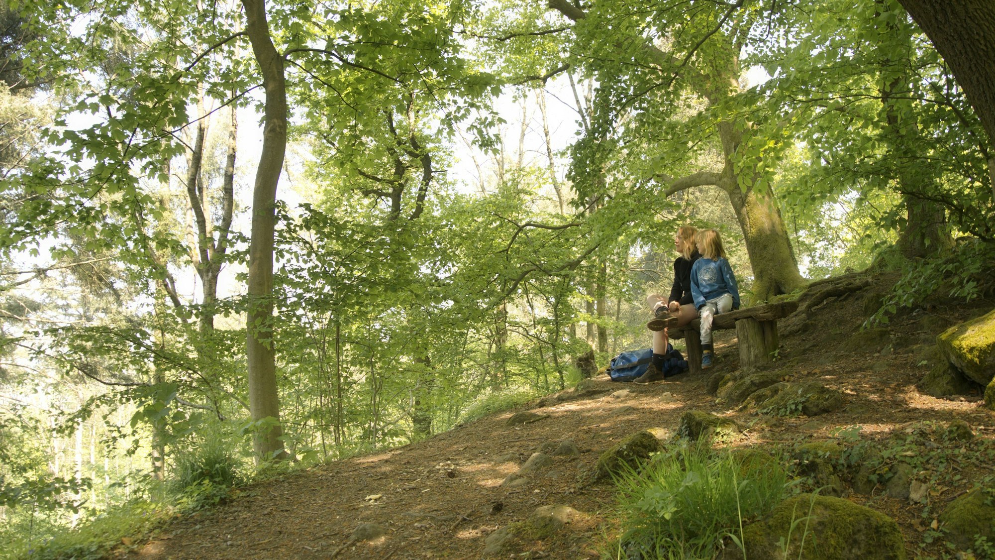 Eine Mutter und ihr Sohn sitzen auf der Bank des Kleinen Oelbergs im Siebengebirge.