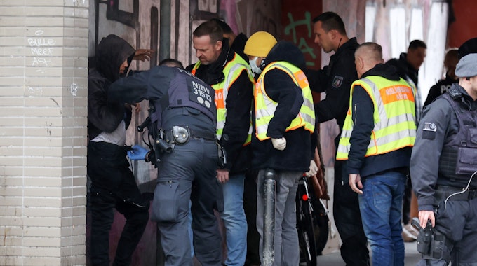 Polizisten und städtische Mitarbeiter kontrollieren einen Mann an der Kalk-Mülheimer Straße.