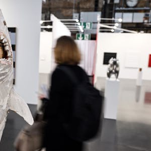 Ausstellungsbesucher gehen durch die Messehalle der Kunstmesse Art Düsseldorf, links das Werk Figurensäule Hai von Stephan Balkenhol.&nbsp;