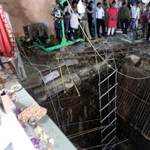 Indien, Indore: Menschen stehen neben einem alten Brunnenbauwerk, über das ein Tempelboden gebaut wurde, der eingebrochen ist.