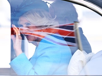 König Charles III. von Großbritannien (verdeckt) und Königsgemahlin Camilla kommen am Flughafen Berlin an. Im Glas des Autofensters spiegelt sich die britische Flagge.
