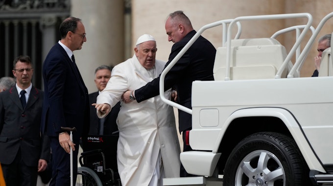 Papst Franziskus (2.v.r) wird am Ende der wöchentlichen Generalaudienz auf dem Petersplatz in sein Auto geholfen, während Massimiliano Strappetti (l), persönlicher medizinischer Betreuer des Papstes, seinen Stock hält.&nbsp;