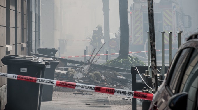 Trümmer liegen nach der Explosion auf der verrauchten Augustastraße in Opladen.
