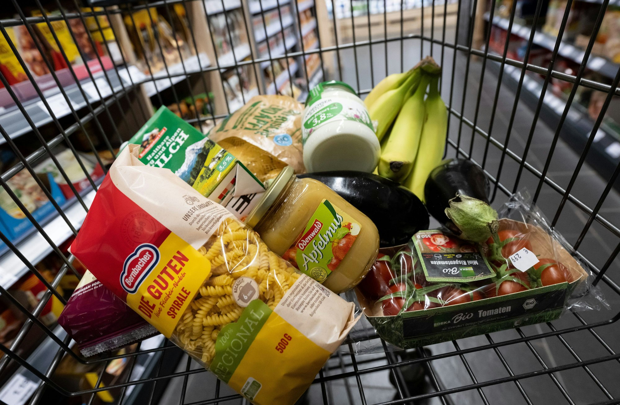 Verschiedene Lebensmittel liegen in einem Supermarkt in einem Einkaufswagen.