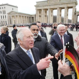 König Charles III. von Großbritannien am Brandenburger Tor mit Bundespräsident Frank-Walter Steinmeier. Ihm gegenüber steht ein Mann mit einer Krone der Fast-Food-Kette „Burger King“.