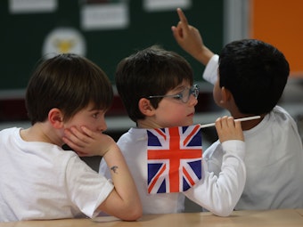 Schüler halten britische Fähnchen während sie in der Rudolf-Roß-Grundschule auf den Besuch der britischen Königsgemahlin Camilla und Elke Büdenbender, der Frau des Bundespräsidenten, warten.