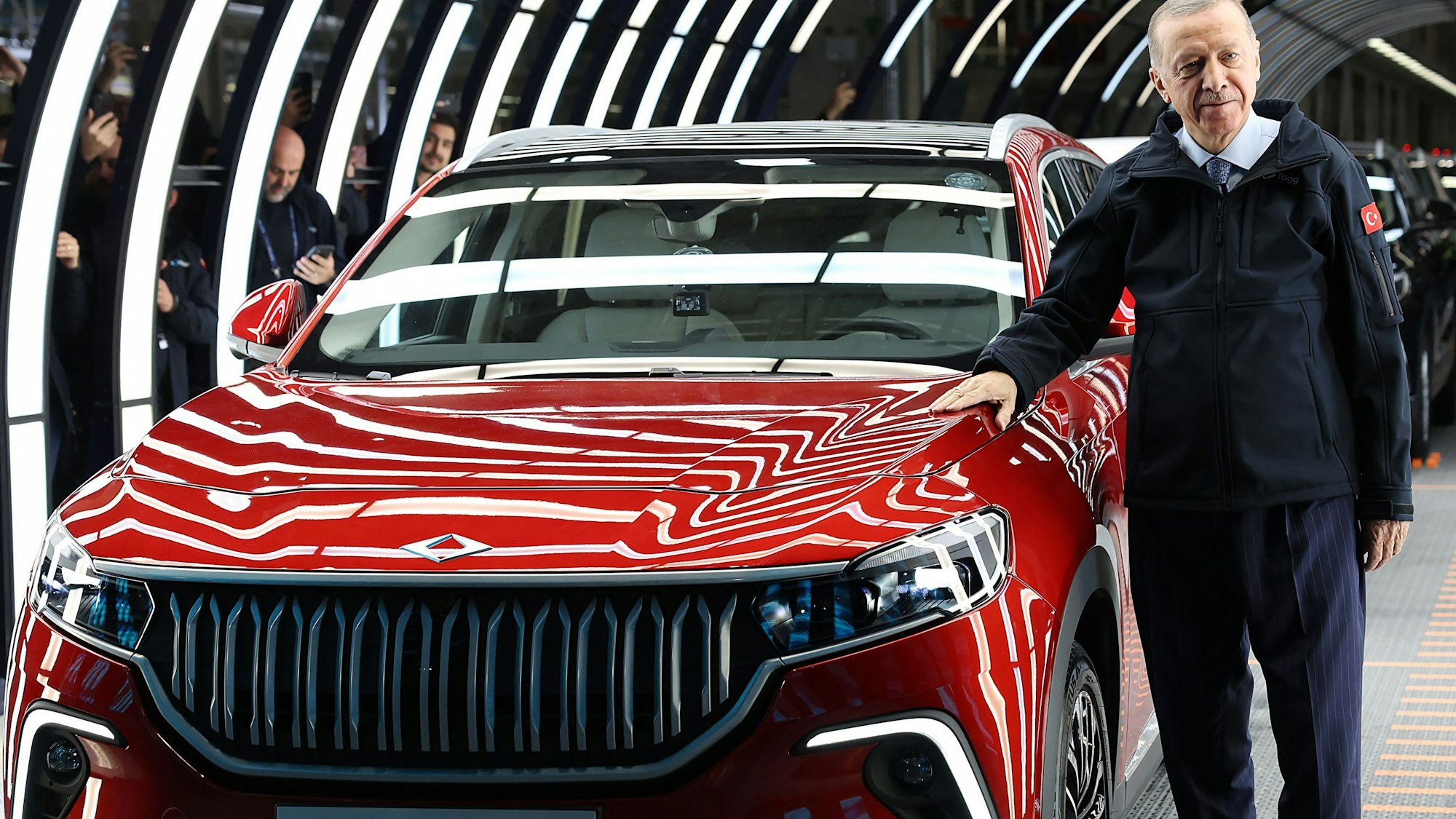 Der türkische Präsident Recep Tayyip Erdogan posiert mit einem roten Auto.