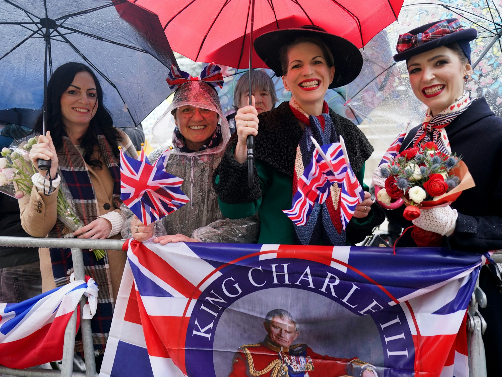 Royal-Fans warten bei Regen am Rathausmarkt vor dem Hamburger Rathaus auf die Ankunft des britischen Königs.