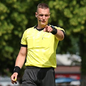 Tobias Esch beim Pfeifen eines Fußballspiels. Mit dem Finger zeigt er nach vorne.