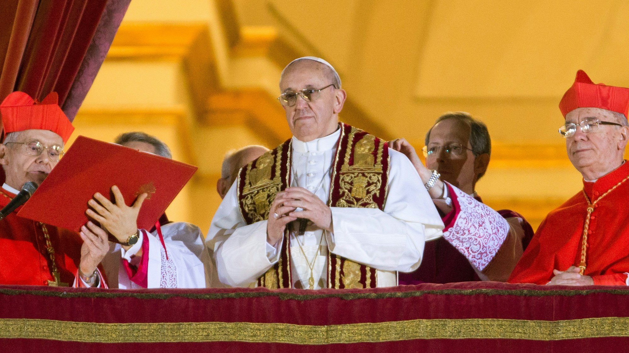 Papst Franziskus (Mitte) auf einem Archivfoto am Abend seiner Wahl am 13. März. Er steht mit zwei Kardinälen an seiner Seite auf dem Balkon des Petersdoms in Rom.
