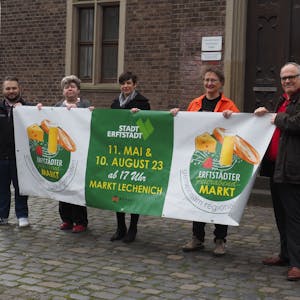 Die zwei Männer und drei Frauen halten das grün-weiße Banner mit dem Logo des geplanten Feierabendmarktes in den Händen.&nbsp;