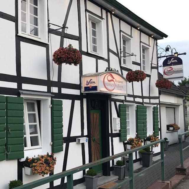 Die Fassade der Cramer Stuben in Odenthal, ein Fachwerkhaus mit grünen Fensterläden.