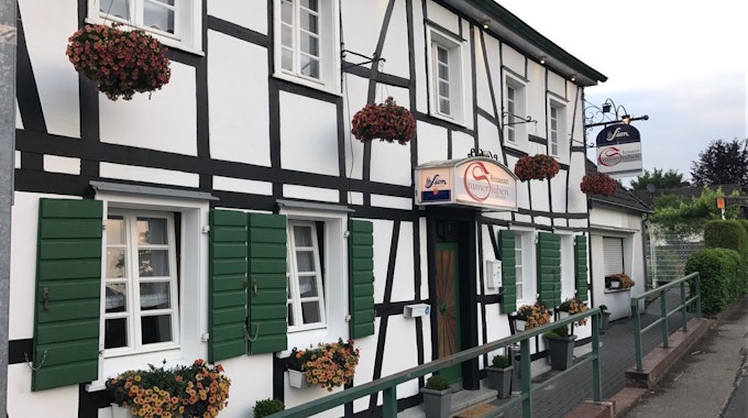 Die Fassade der Cramer Stuben in Odenthal, ein Fachwerkhaus mit grünen Fensterläden.