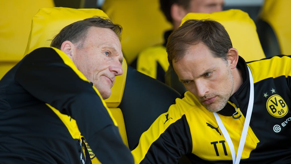 Dortmunds damaliger Trainer Thomas Tuchel (r) sitzt einem Spiel auf der Trainerbank und unterhält sich mit Dortmunds Geschäftsführer Hans-Joachim Watzke (l).