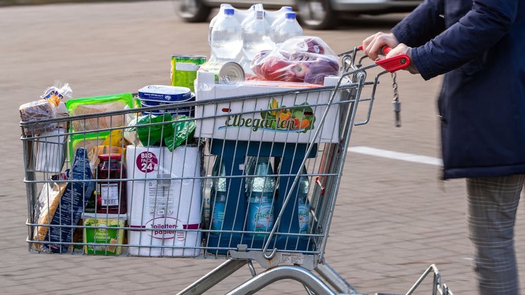 Auf dem Bild sehen sie einen mit Lebensmitteln gefüllten Einkaufswagen auf einem Supermarktparkplatz.