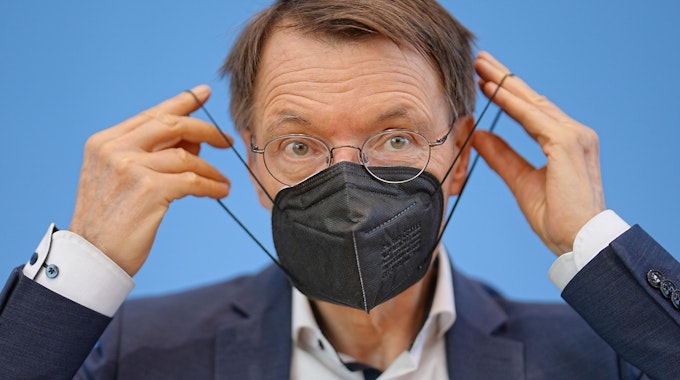 Bundesgesundheitsminister Karl Lauterbach (SPD) zieht eine FFP2-Maske am Ende einer Pressekonferenz zur Corona-Lage im Sommer 2022 in der Bundespressekonferenz auf. Die Maskenpflicht ist bald Geschichte.