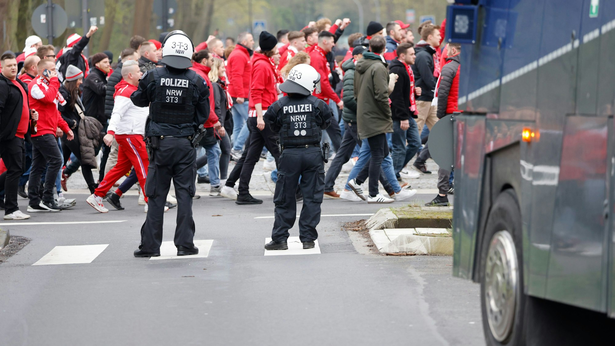 Auf dem Weg ins Stadion ziehen Fußballfans des 1. FC Köln an einem Wasserwerfer der Polizei vorbei.