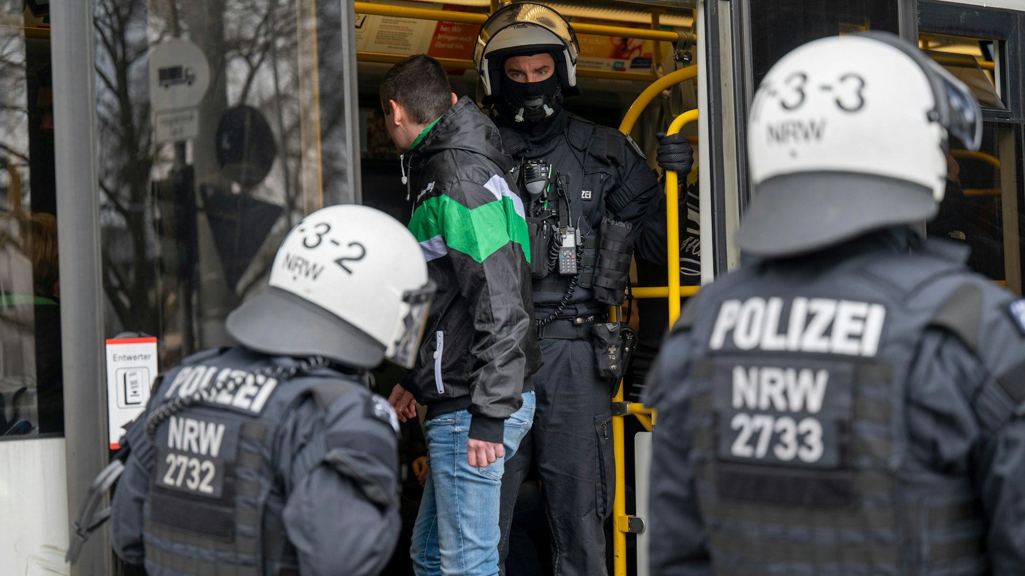 Am Bahnhof Ehrenfeld steigt ein Mönchengladbach-Fan umringt von Polizisten in eine Straßenbahn zum Stadion ein.