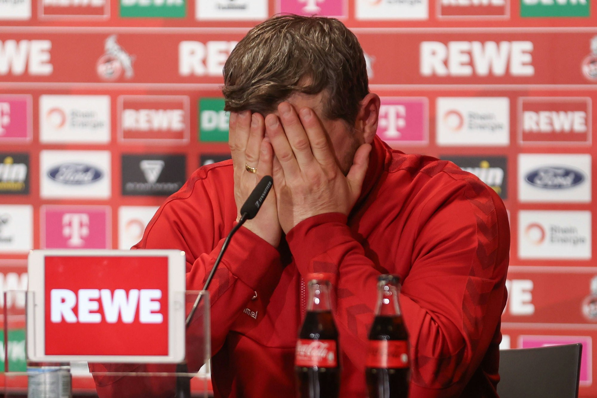 FC-Trainer Steffen Baumgart schlägt auf der Pressekonferenz nach dem Spiel die Hände vor dem Kopf zusammen.