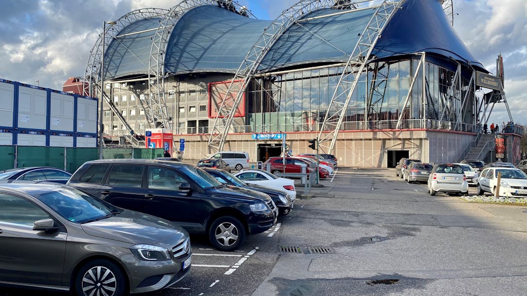 Autos stehen in Parkbuchten. Im Hintergrund ist der Kölner Musical Dome zu sehen.