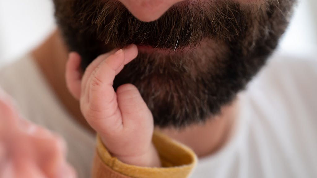 Ein Baby fasst seinem Vater in den Bart.