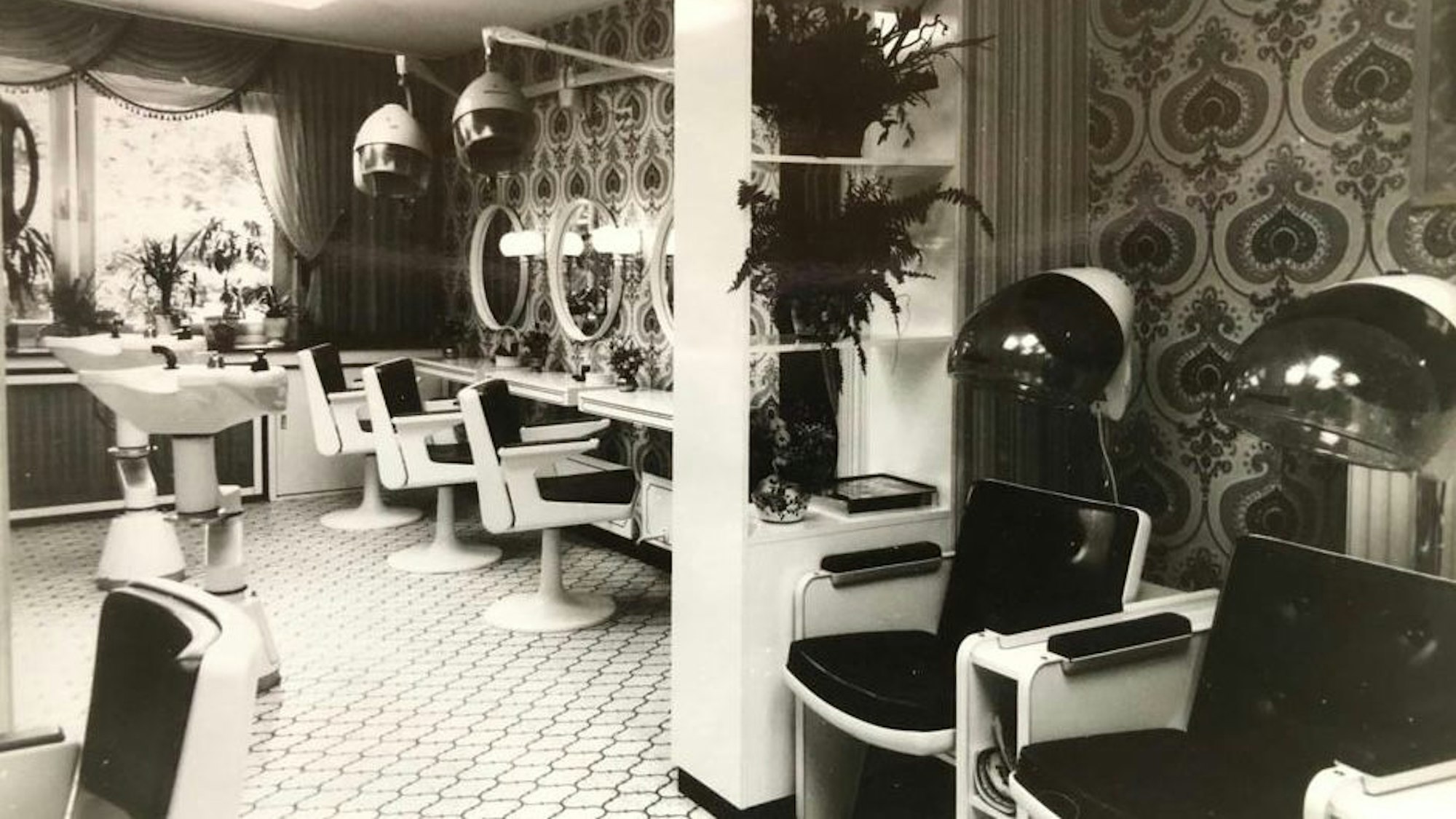 In einem Friseursalon stehen alte Stühle und Hauben.