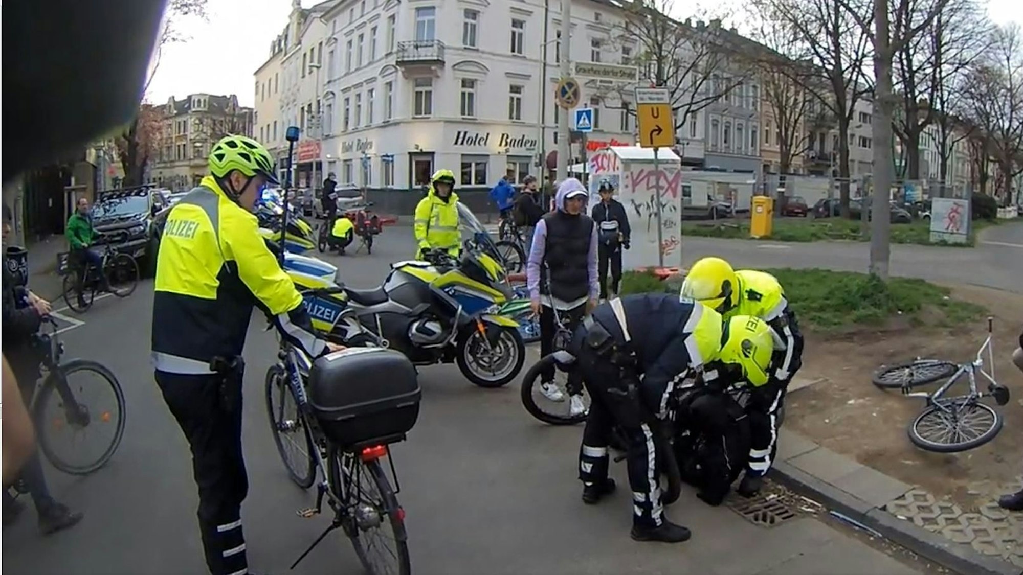 Screenshot aus einem Twitter-Video. Polizei-Einsatz am Rand der Fahrrad-Demonstration Critical Mass in Bonn. Mehrere Polizisten stehen um das Fahrrad eines Jungen. Der Junge liegt am Boden.