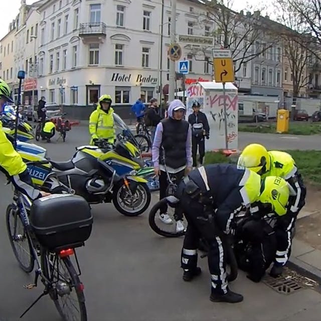Screenshot aus einem Twitter-Video. Polizei-Einsatz am Rand der Fahrrad-Demonstration Critical Mass in Bonn. Mehrere Polizisten stehen um das Fahrrad eines Jungen. Der Junge liegt am Boden.