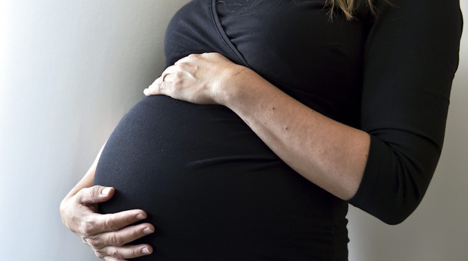Eine schwangere Frau hält sich den Bauch. (Symbolbild)