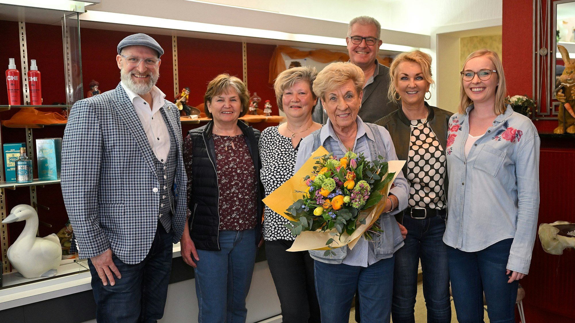 Ingrid Wilms steht mit ihren Mitarbeiterinnen und ihrer Familie im Laden. Sie hält einen Blumenstrauß in den Händen.