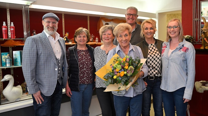 Ingrid Wilms steht mit ihren Mitarbeiterinnen und ihrer Familie im Laden. Sie hält einen Blumenstrauß in den Händen.&nbsp;