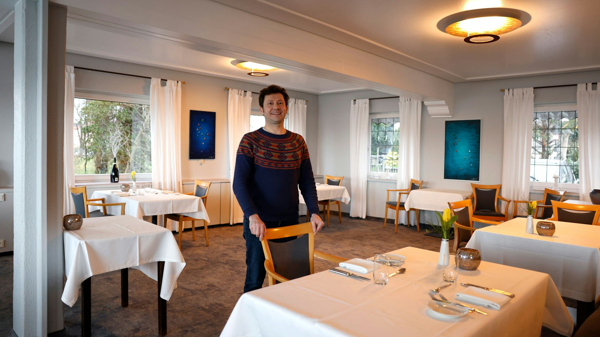 Thomas Lösche steht in seinem Sternerestaurant "Zur Tant" in Köln. Die Einrichtung ist schlicht und dominiert von der Farbe Weiß.