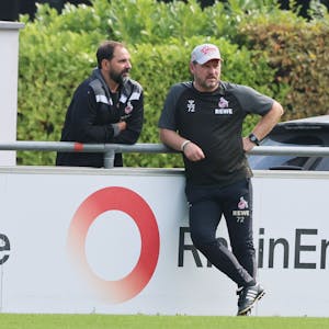 FC-Nachwuchstrainer Stefan Ruthenbeck und Chef-Coach Steffen Baumgart stehen am Geißbockheim zusammen.